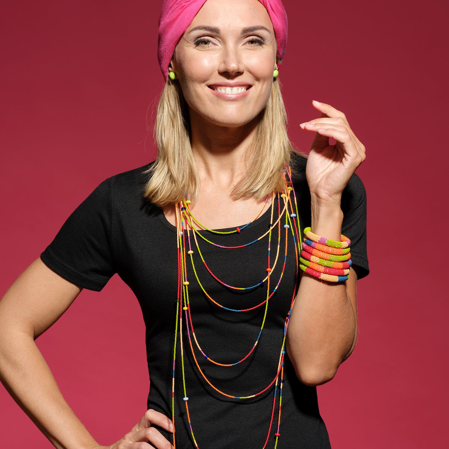 12 foot long colorful necklace looed and layered with a stack of beaded bracelets and small green glass stud earrings