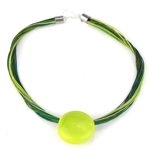 A vibrant necklace featuring a hand-blown green glass focal bead strung on multi-strand waxed cord in shades of green. Finished with a sterling silver hook-and-loop clasp, this piece adds a fresh, colorful accent to any outfit.