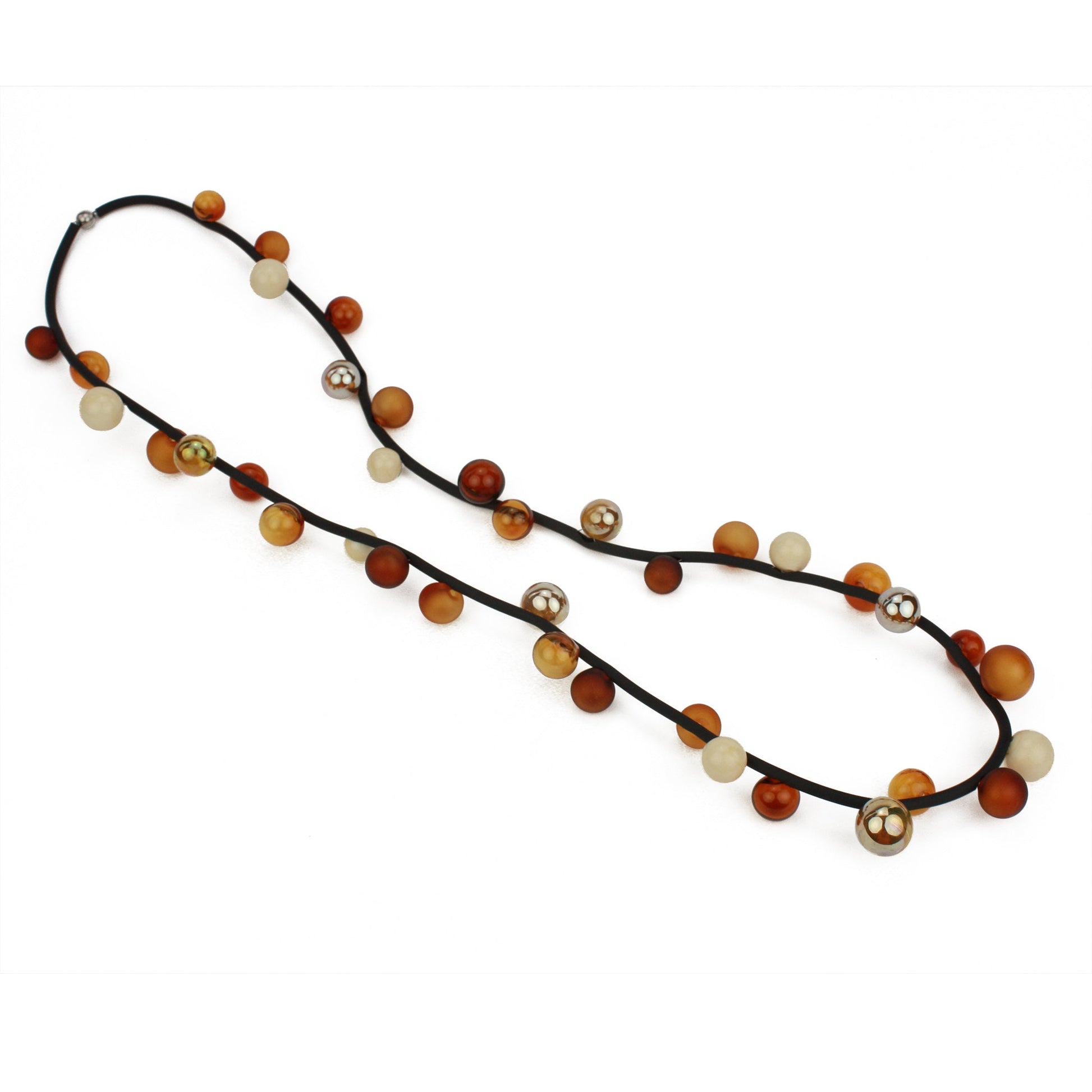 The "Bolla" necklace featuring hand-blown glass beads in amber, gold, and cream tones, strung on a steel cable through a rubber cord, worn long or doubled up.