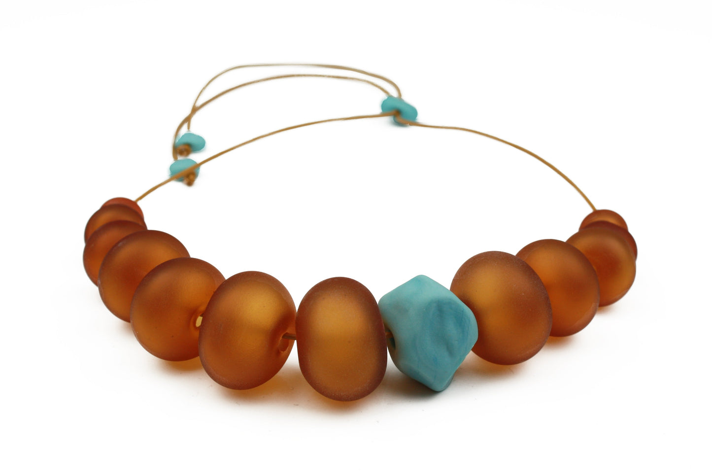Necklace of hand blown and sandblasted hollow beads in velvety shades of amber glass paired with a turquoise glass nugget bead and strung on adjustable leather