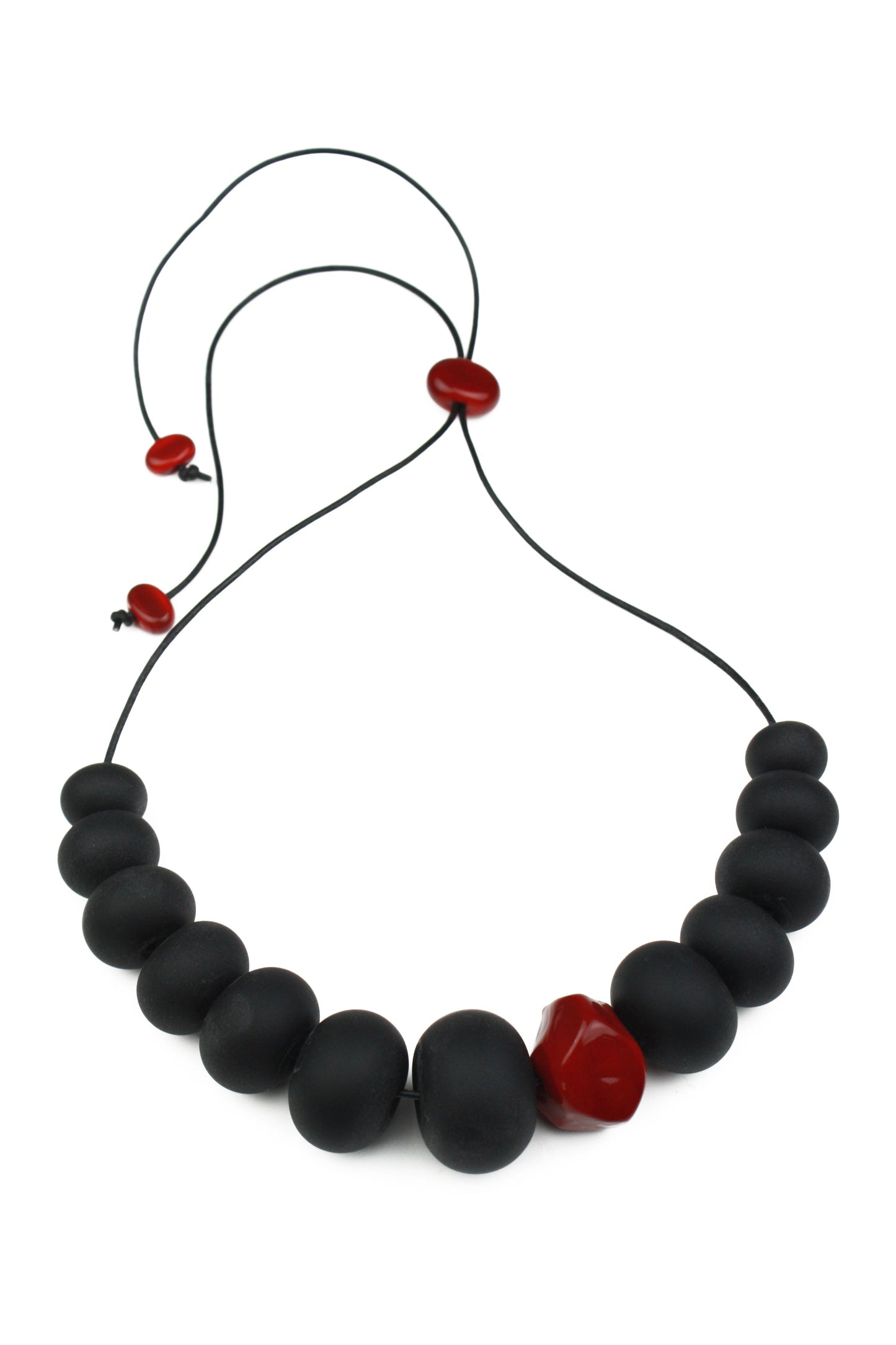 Necklace of hand blown and sandblasted hollow beads in velvety black glass paired with a red glass nugget bead and strung on adjustable leather