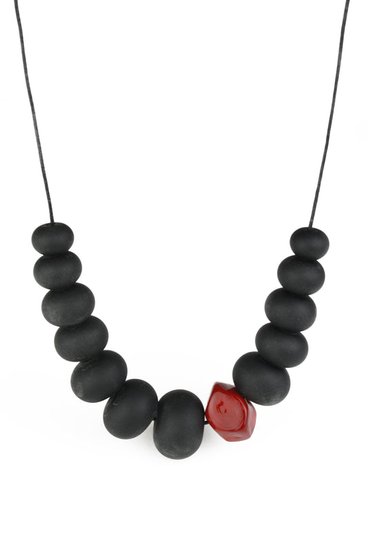 Necklace of hand blown and sandblasted hollow beads in velvety black glass paired with a red glass nugget bead and strung on adjustable leather