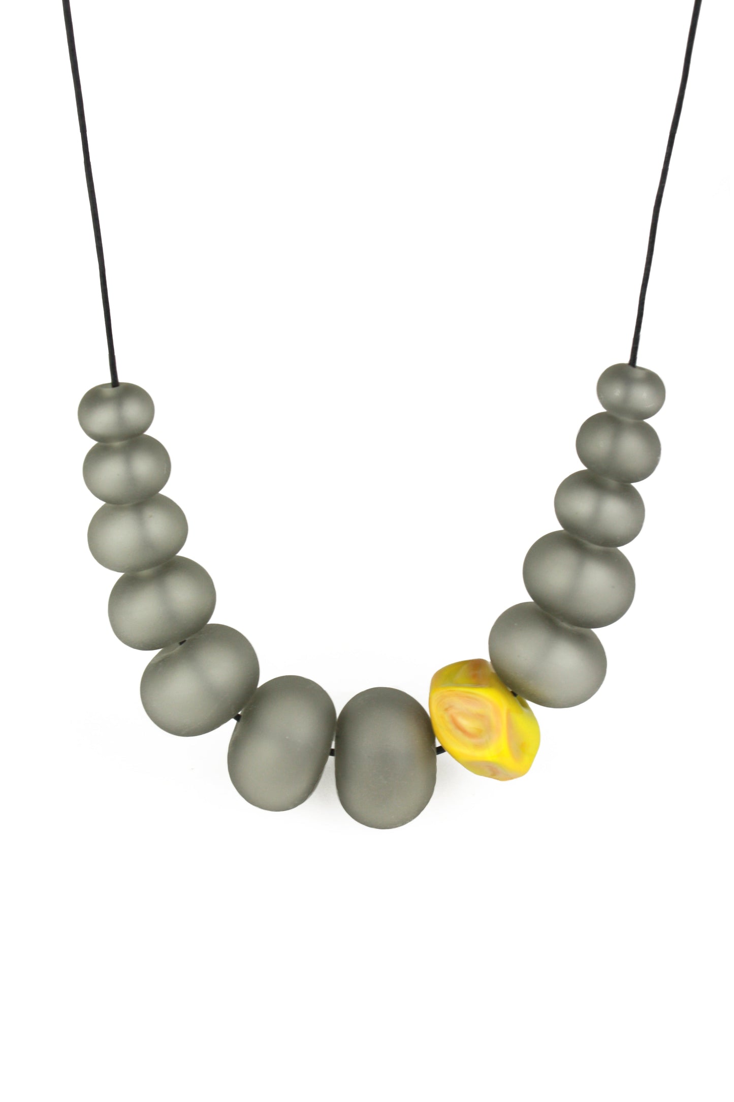 Necklace of hand blown and sandblasted hollow beads in velvety grey glass paired with a ochre yellow glass nugget bead and strung on adjustable leather