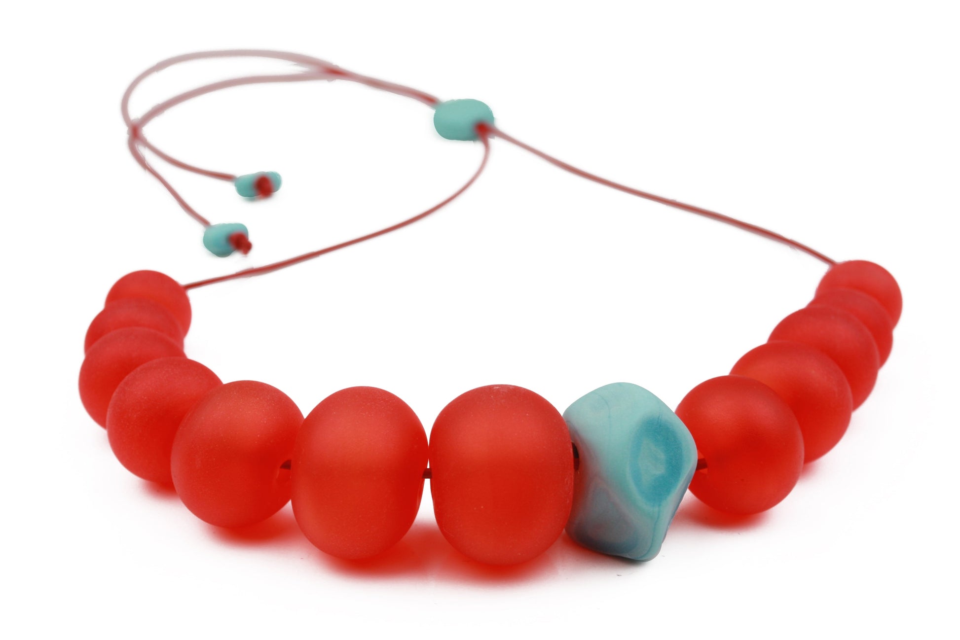 Necklace of hand blown and sandblasted hollow beads in velvety cherry red glass paired with a turquoise glass nugget bead and strung on adjustable leather